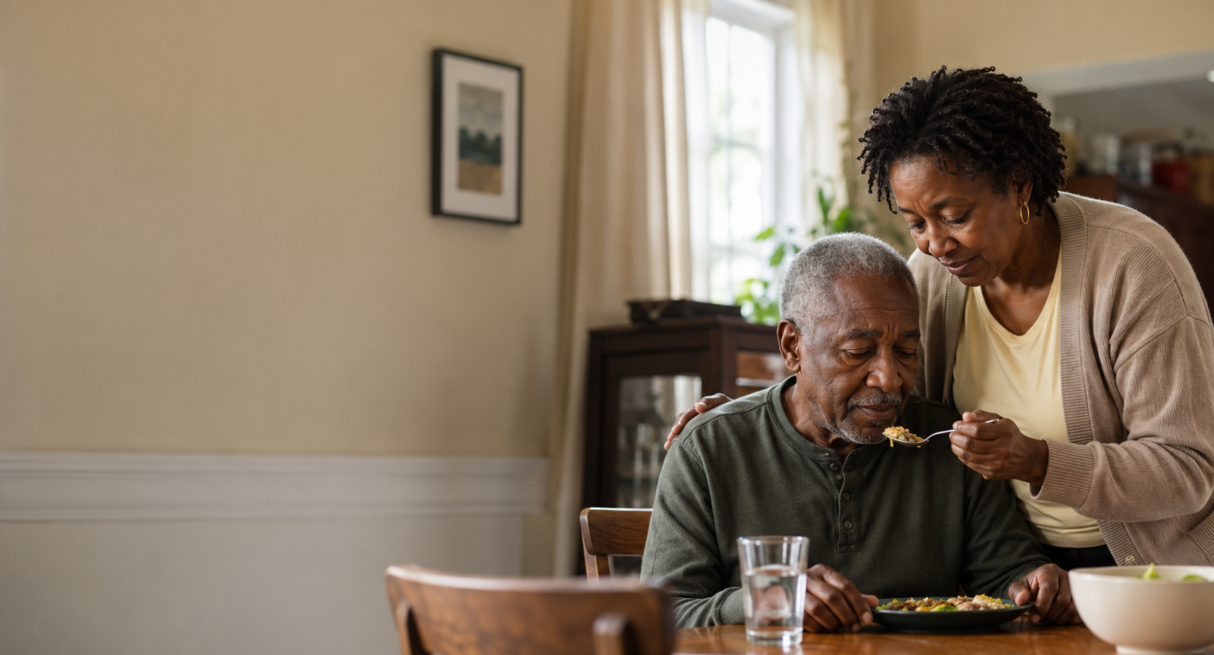 An adult daughter helping her older father during a quiet meal at home